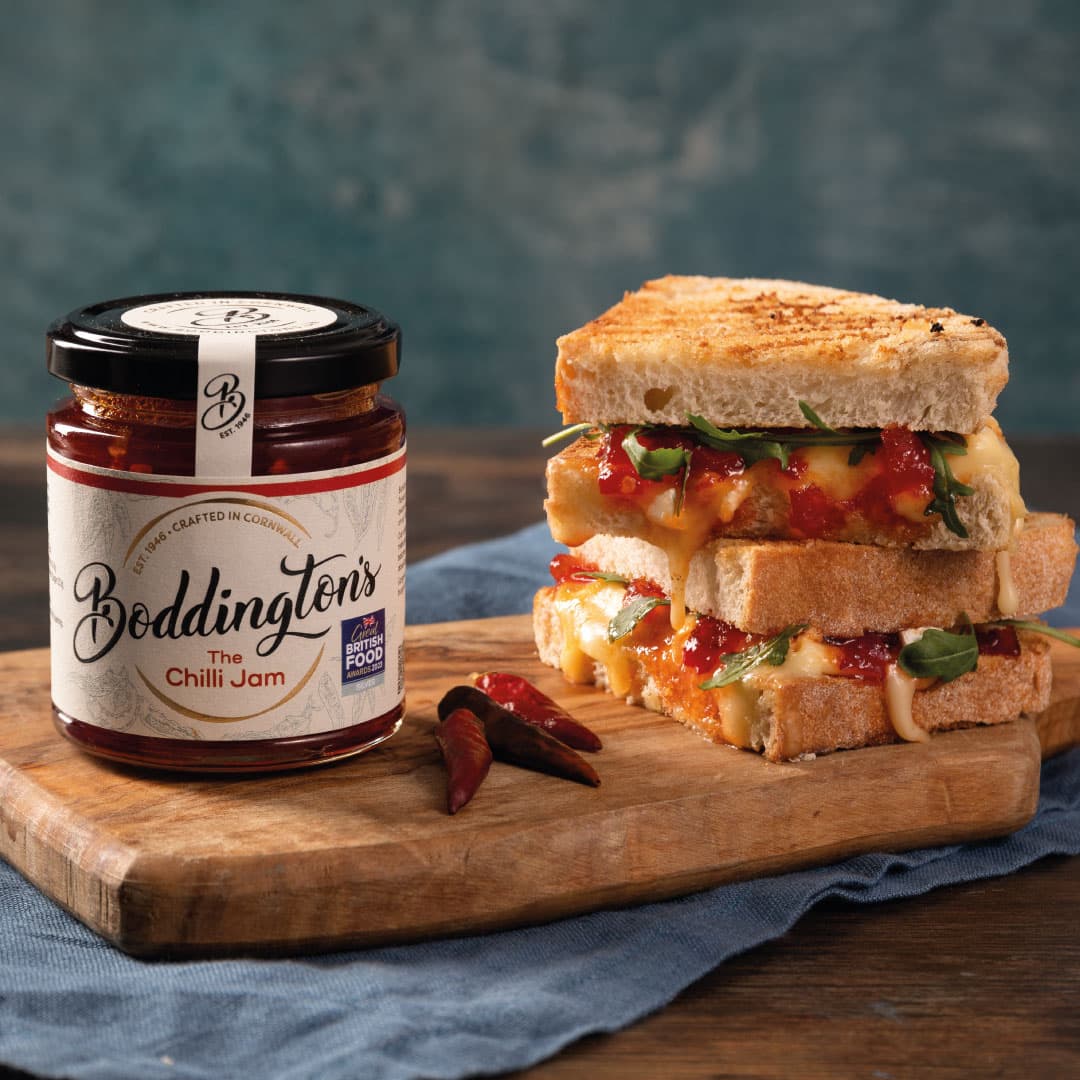 Jar of Boddington's chilli jam beside a toasted cheese and chilli sandwich