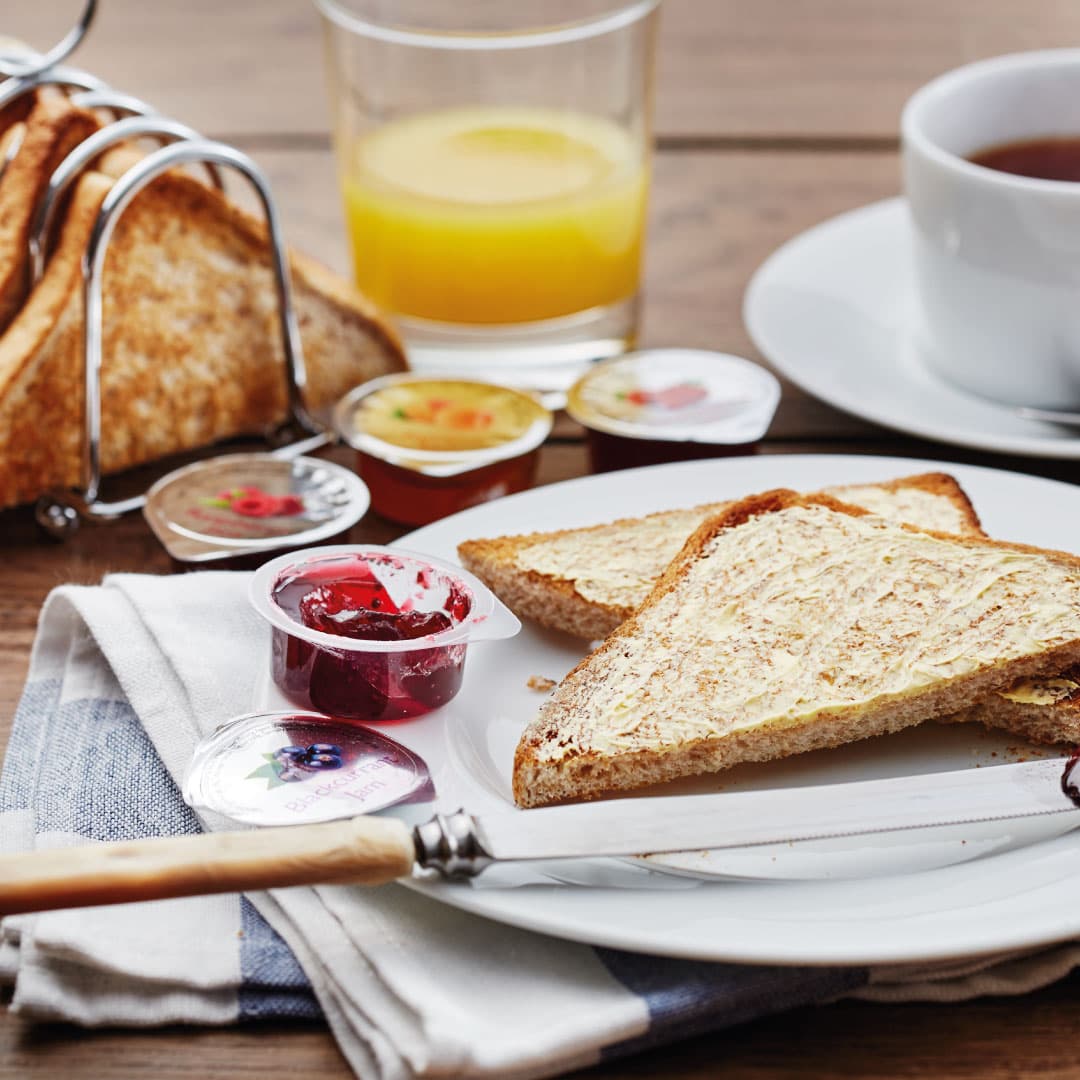 Buttered toast with portion pots of jam, orange juice and tea