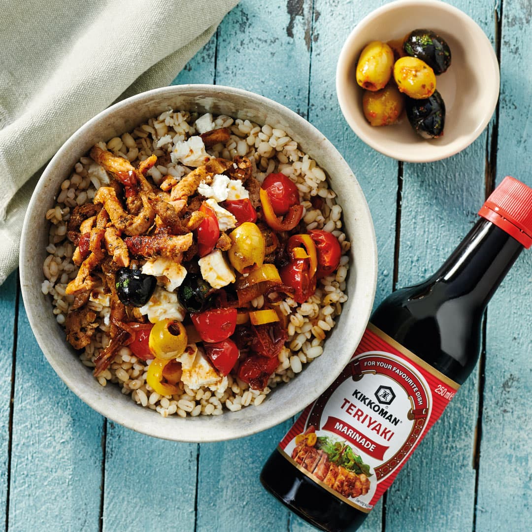 Kikkoman teriyaki marinade beside a bowl of chicken, pearl barley and tomatoes