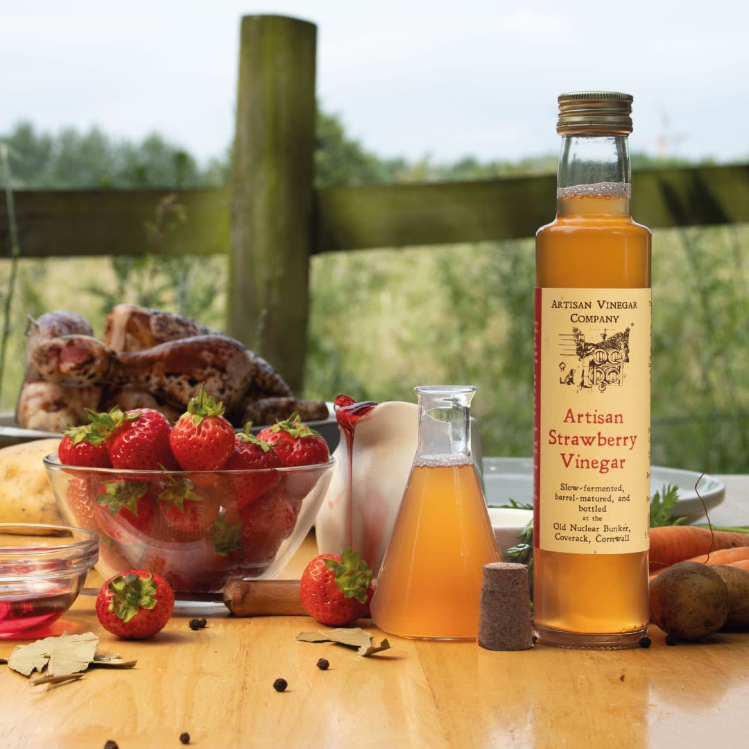 Bottle of artisan strawberry vinegar with fresh strawberries on an outdoor table