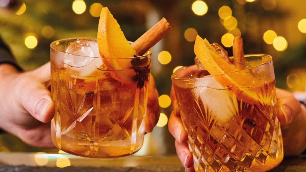 Two spiced cocktails with orange slices and cinnamon sticks