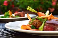 Restaurant plate of steak with roasted carrots and spring onions