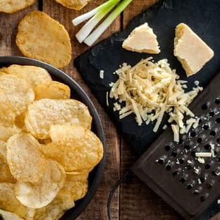 Bowl of crisps beside grated mature cheddar and spring onions