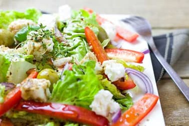 Fresh salad with peppers, feta and leaves on a white plate
