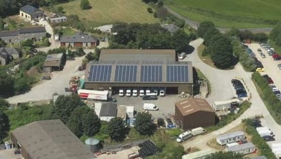 Aerial view of a depot with solar panels, delivery vans and countryside