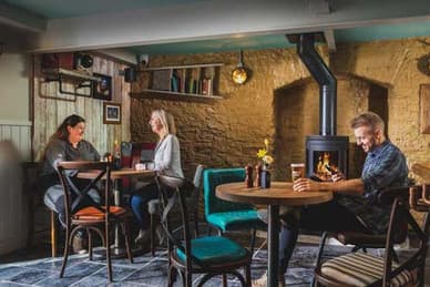 Customers relaxing in a stone-walled pub beside a wood burner