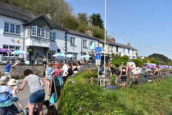 Busy waterside pub on a sunny day with crowds outside