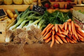 Spring onions and bunches of carrots on a farm shop display