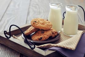 Cookies on a tray with two bottles of milk