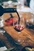 Red wine being poured into a glass at a dinner table