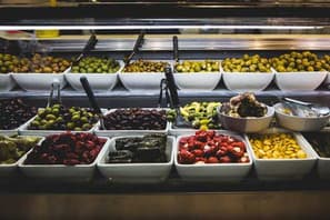 Deli counter of olives, peppers and antipasti in white dishes