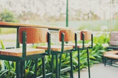Wooden bar stools at an outdoor counter surrounded by greenery