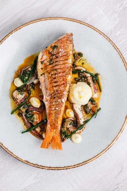Pan-fried red mullet with samphire and sauce on a white plate