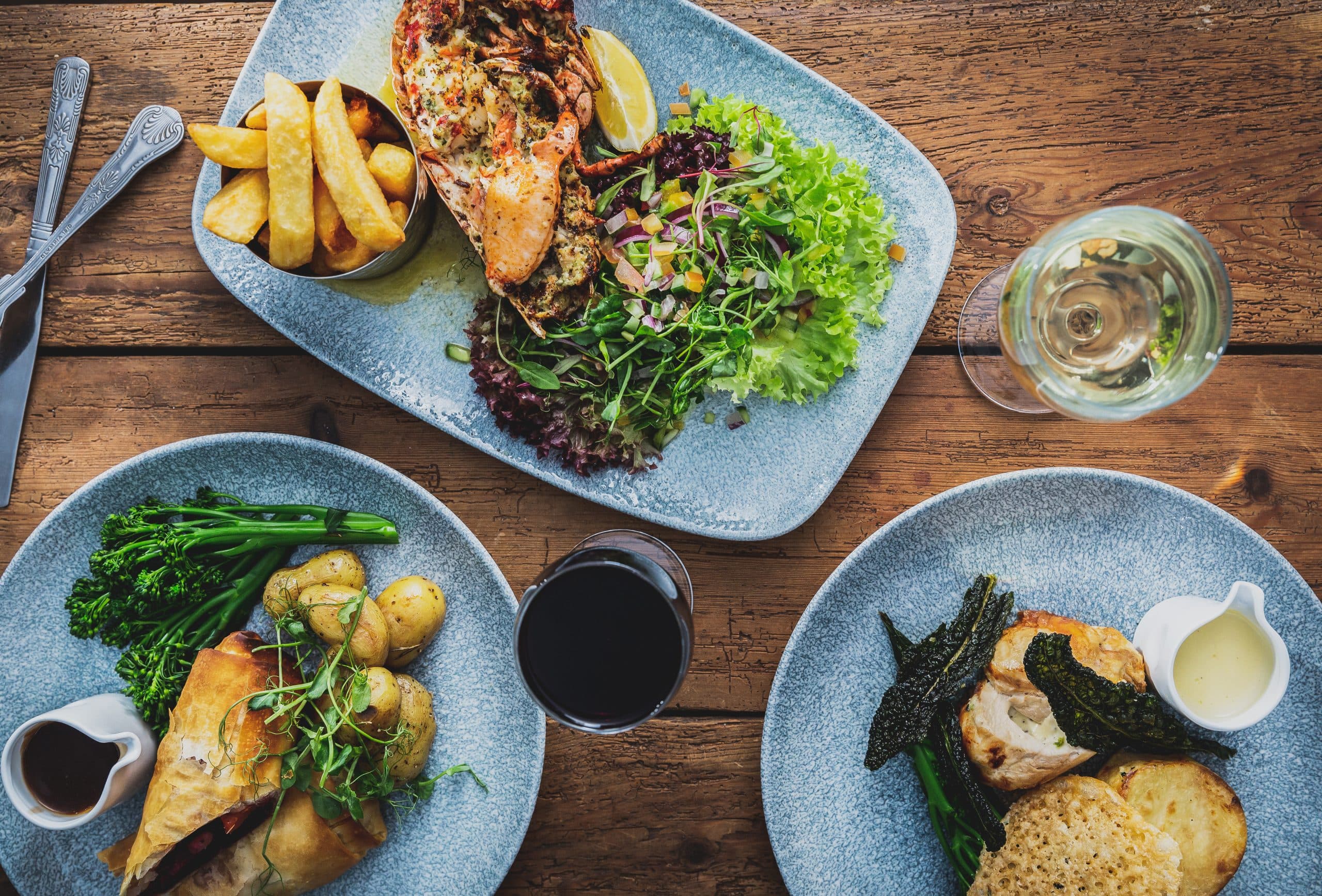 Lobster salad with chips and other plated dishes on a wooden table