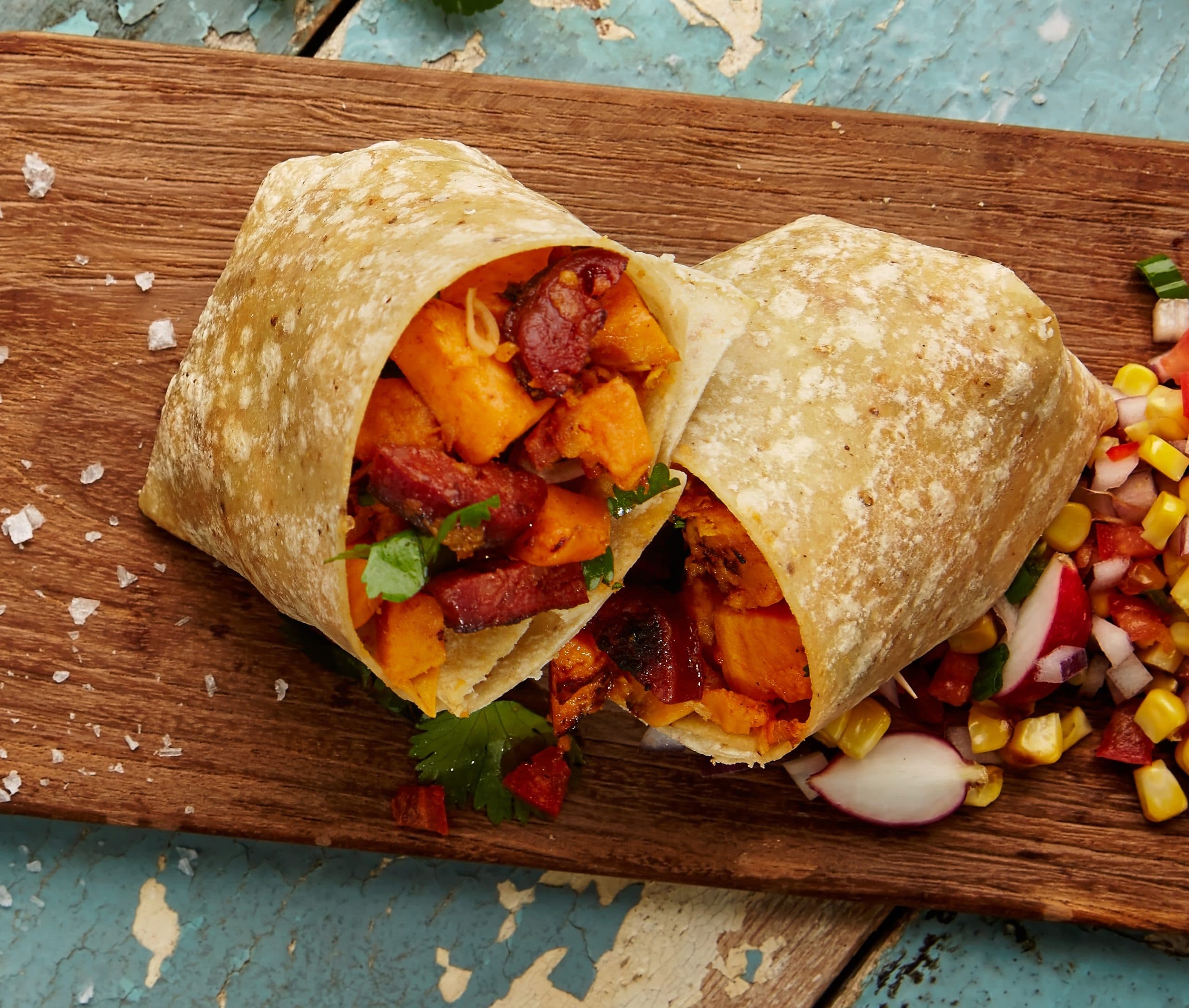 Burrito filled with sweet potato and chorizo on a wooden board