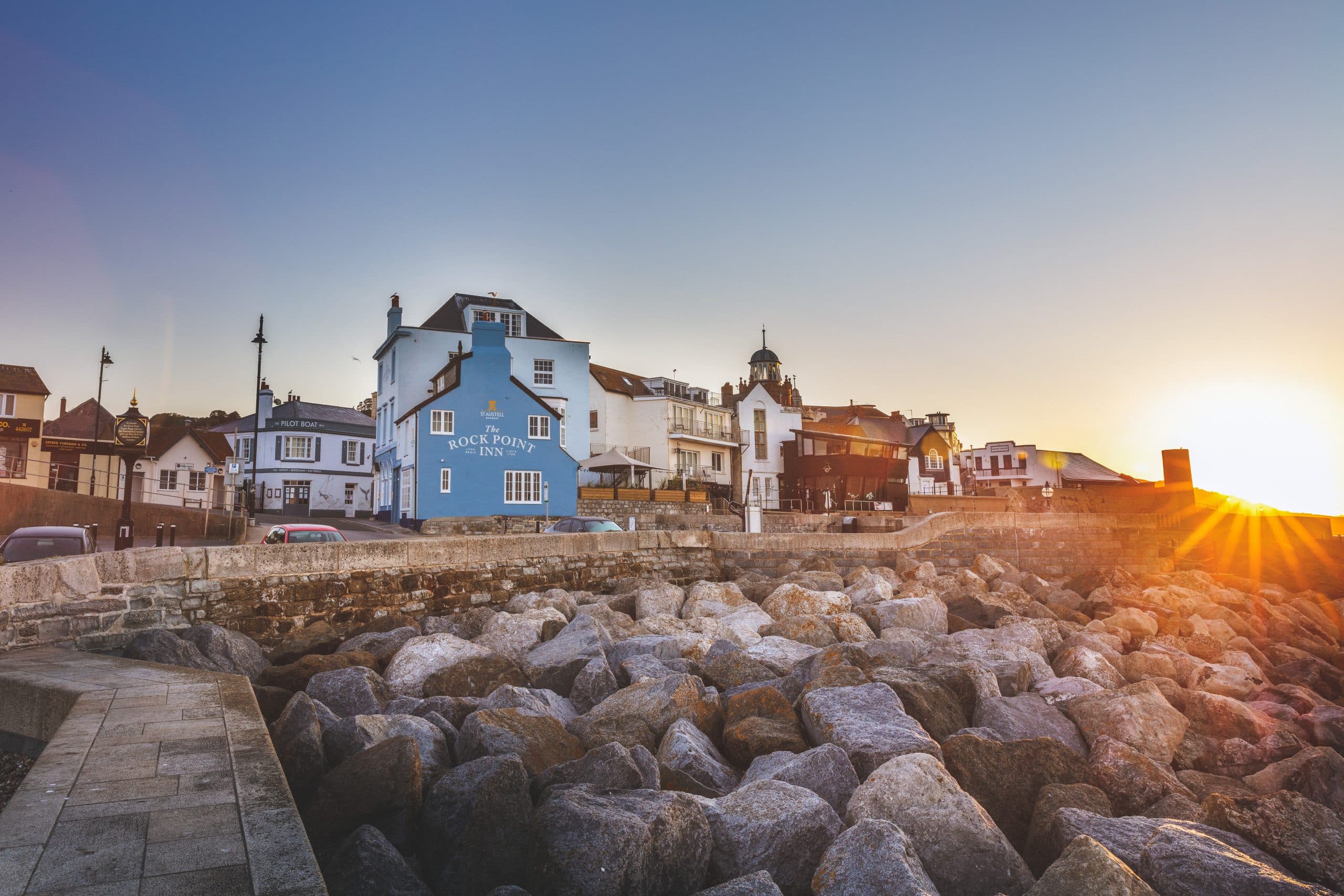 The Rock Point Inn and seafront buildings at sunset beside rocks