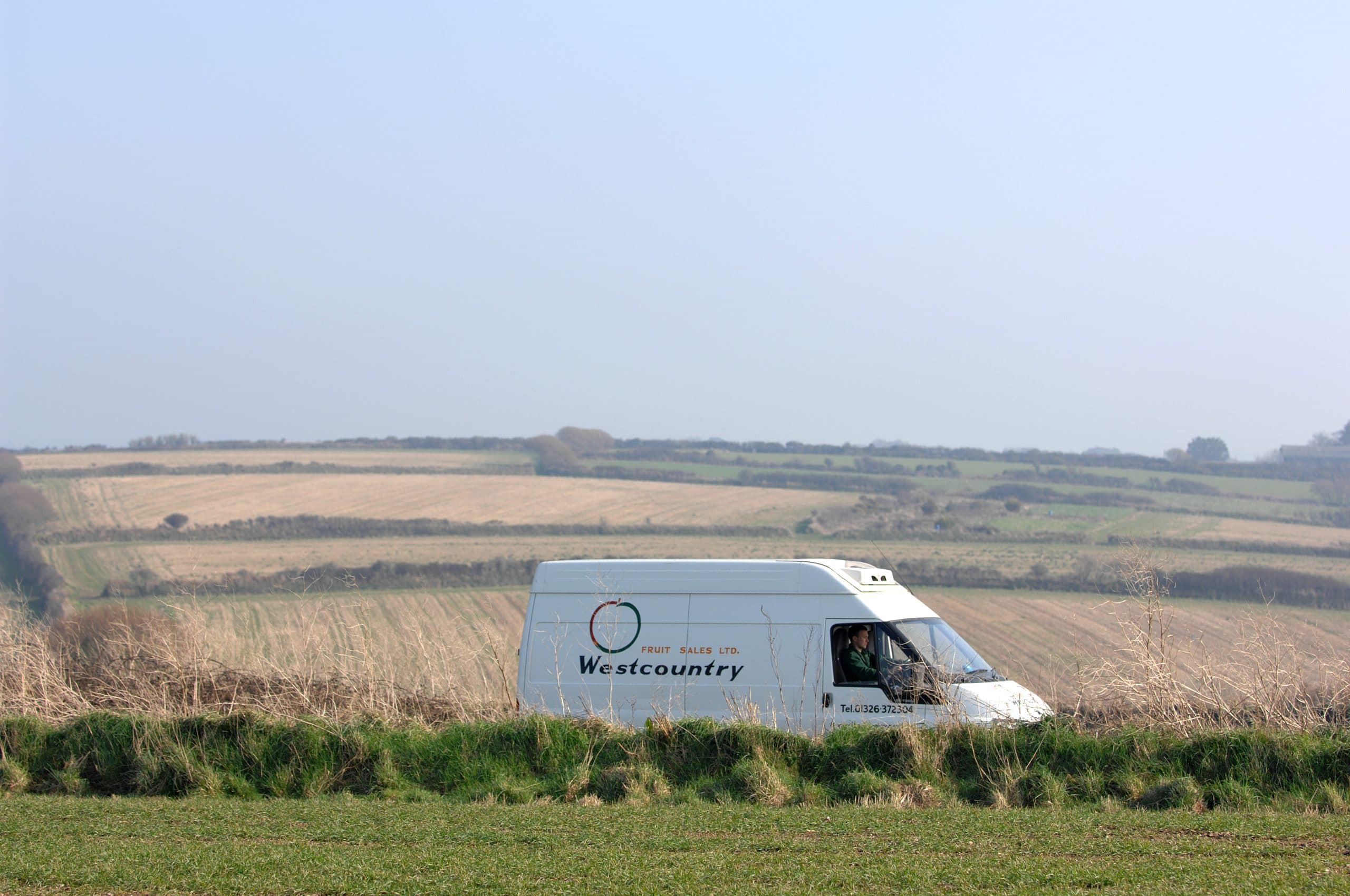 Westcountry van driving through open Cornish farmland