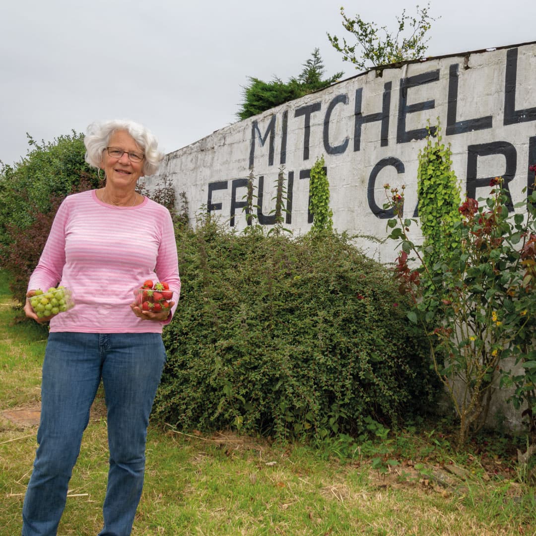 Grower holding punnets of grapes and strawberries outside Mitchell's Fruit Farm