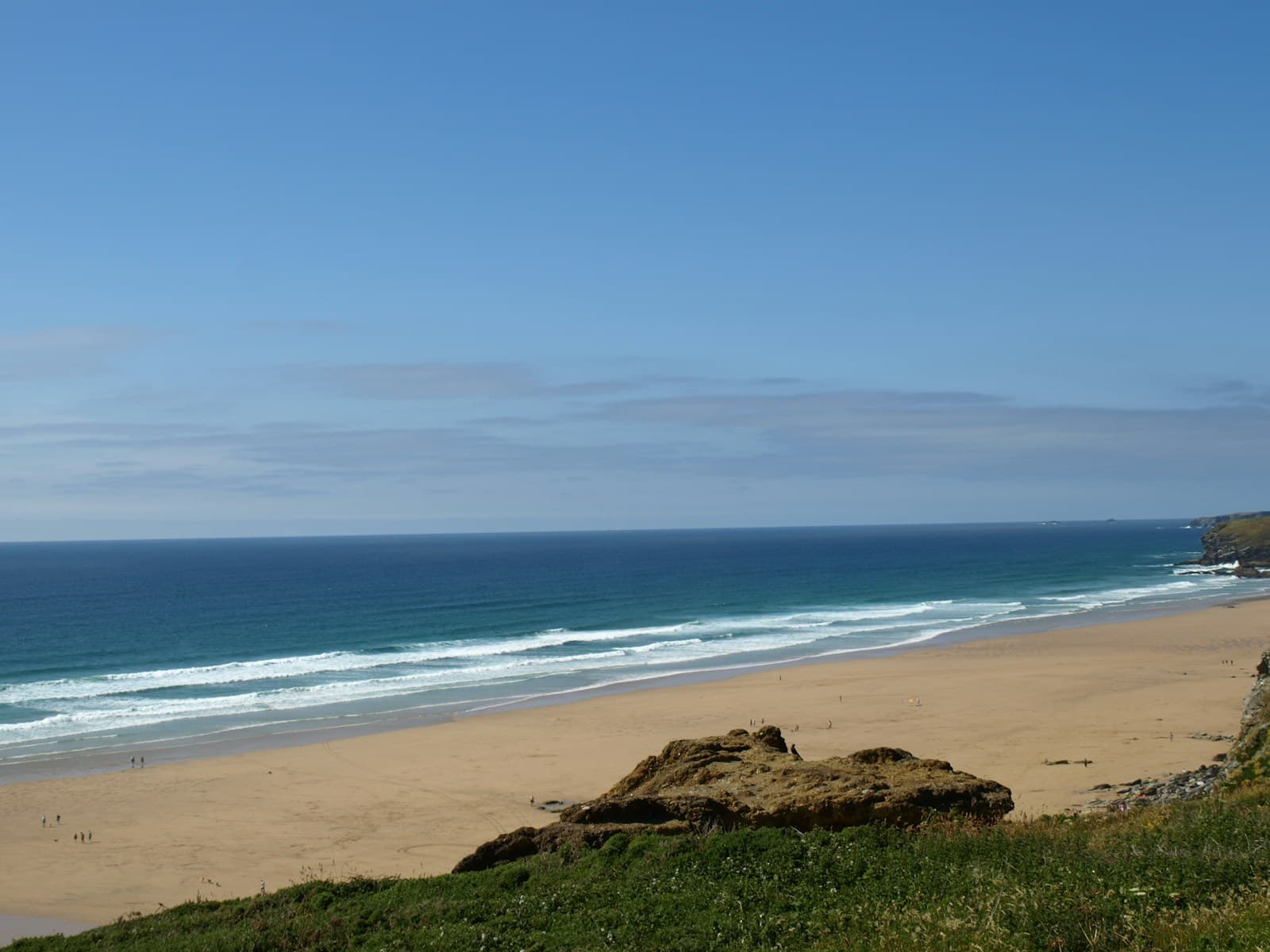 A view of a beach from a hill overlooking the ocean