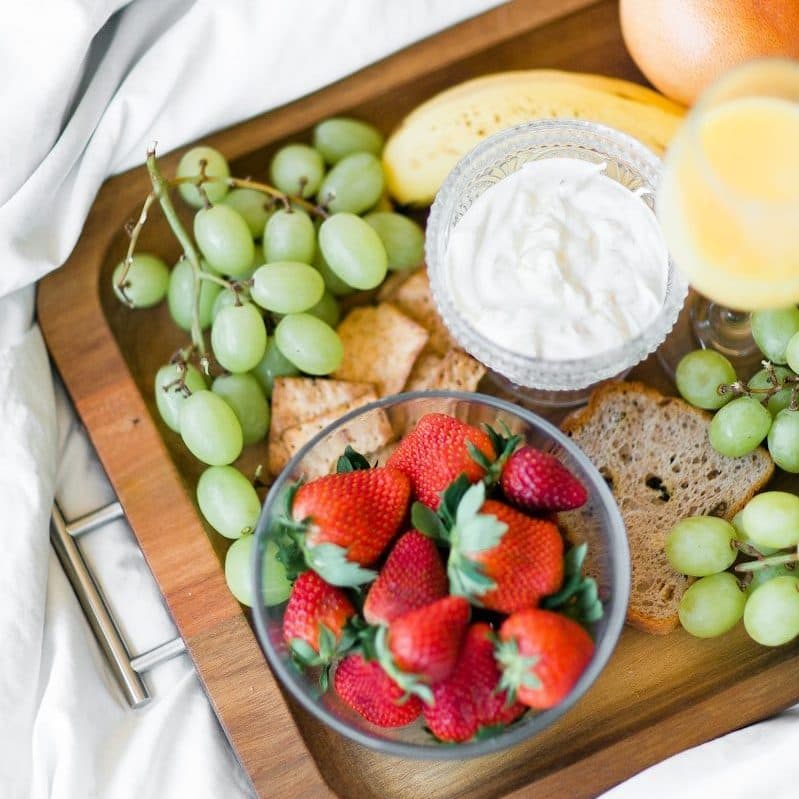 Breakfast tray of strawberries, grapes, yoghurt, crackers and orange juice